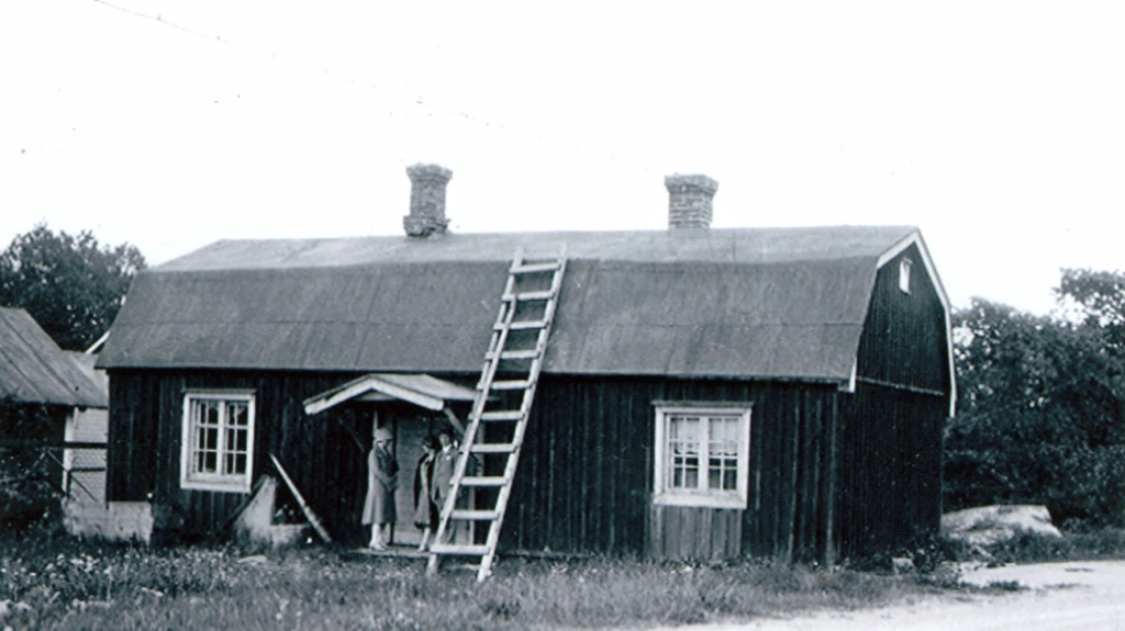 Hangon ensimmäinen museo Fohlinin tupa. Pieni tupa mansardikatolla. Vieraita kuistilla. Hangös första museum, Fohlinska stugan. Gäster på trappan. The first museum, the Fohlin cottage. Guests standing outside the door.