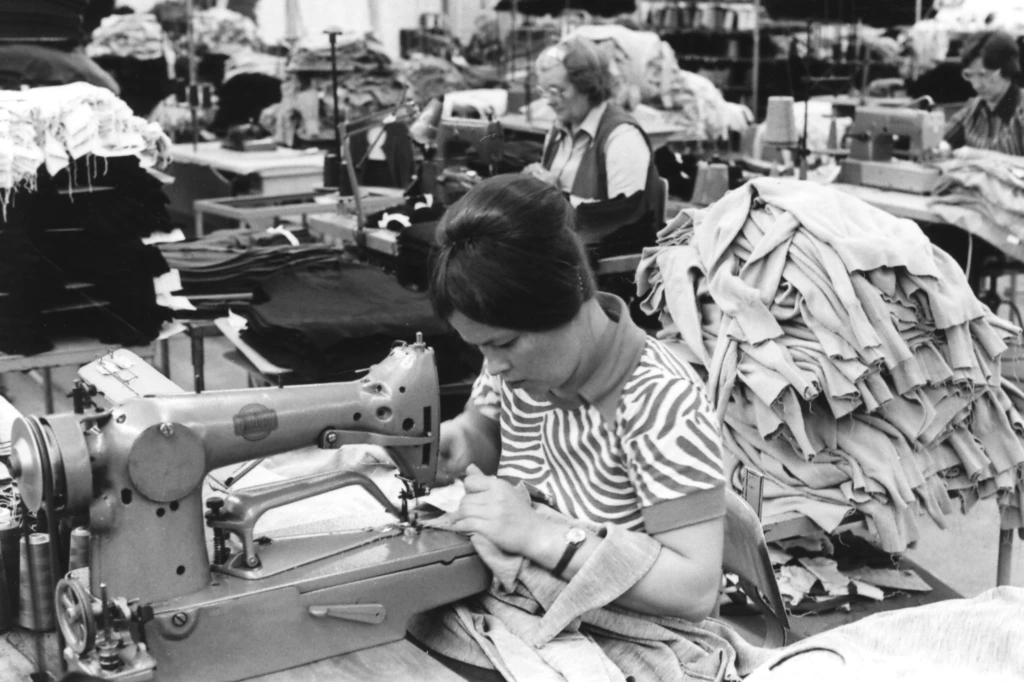 Hyvonin tekstiilitehtaassa. Naiset ompelevat vaatteita. I Hyvons textilfabrik. Kvinnor syr kläder på maskin. The textile factory Hyvon. Women sewing clothes.